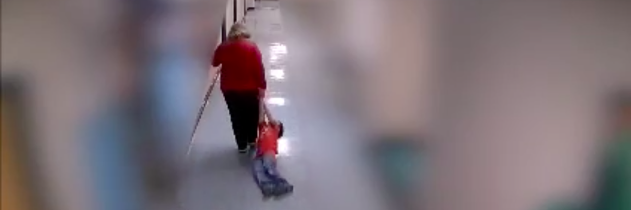 Screenshot of teacher dragging boy down school hallways