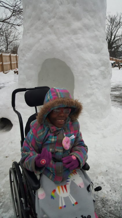Zahara smiling, sitting on her chair with the igloo behind her