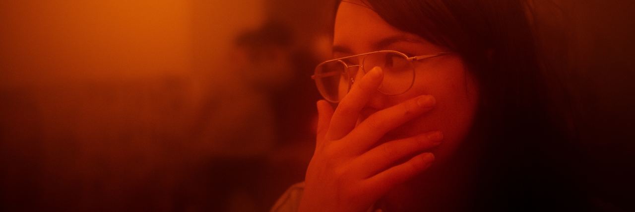 The Truth About Being ‘Triggered’ When You Have PTSD blurred photo of woman in red light looking afraid