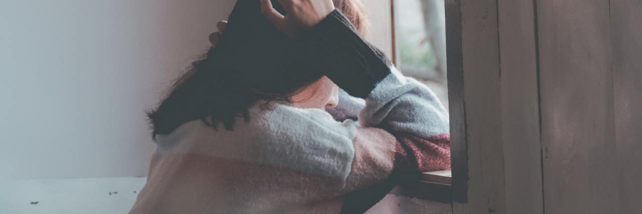 How It Feels When Bipolar Disorder Mania Ends blurred photo of woman leaning on window ledge alone looking sad