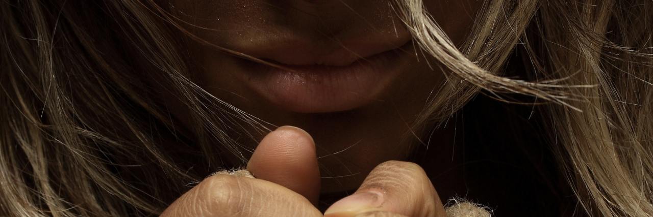 I Was Scared to Tell Anyone That My Partner Hit Me close up of woman's hands tied and face dark under hair