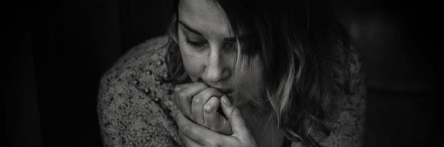 black and white photo of young person with chin resting on hand looking worried or scared