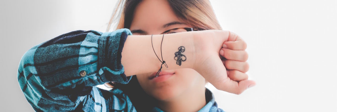 What It's Like to Be Suicidal With Chronic Fatigue Syndrome A woman covering her face with her arm