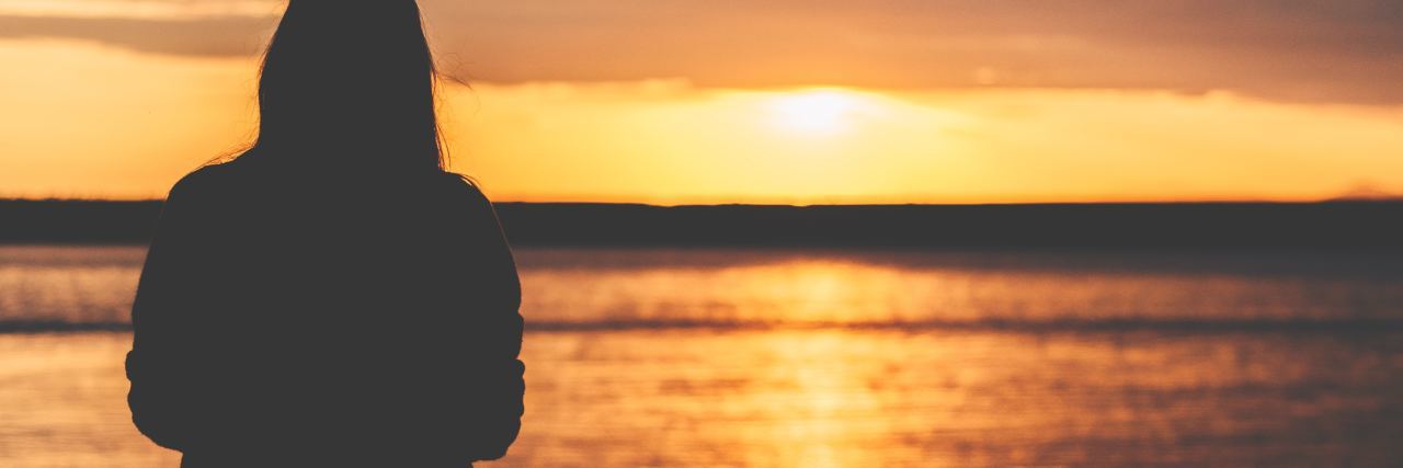 Looking for the Positives of My Childhood Trauma photo of woman watching sunset over water