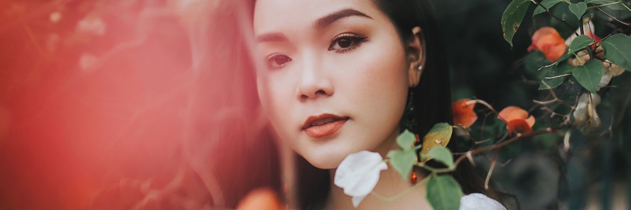 8 Small Strategies I Use to Handle a Depressive Episode woman standing behind leaves