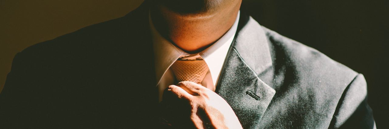 close up photo of man fixing tie on suit