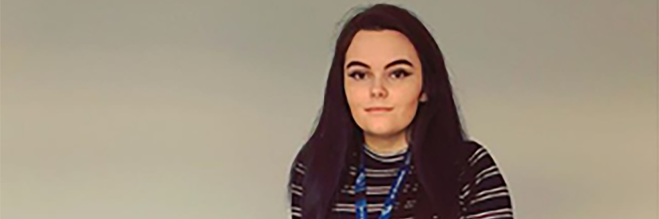 Using a Mobility Aid With Ehlers-Danlos Syndrome Sophie standing indoors with her crutch.