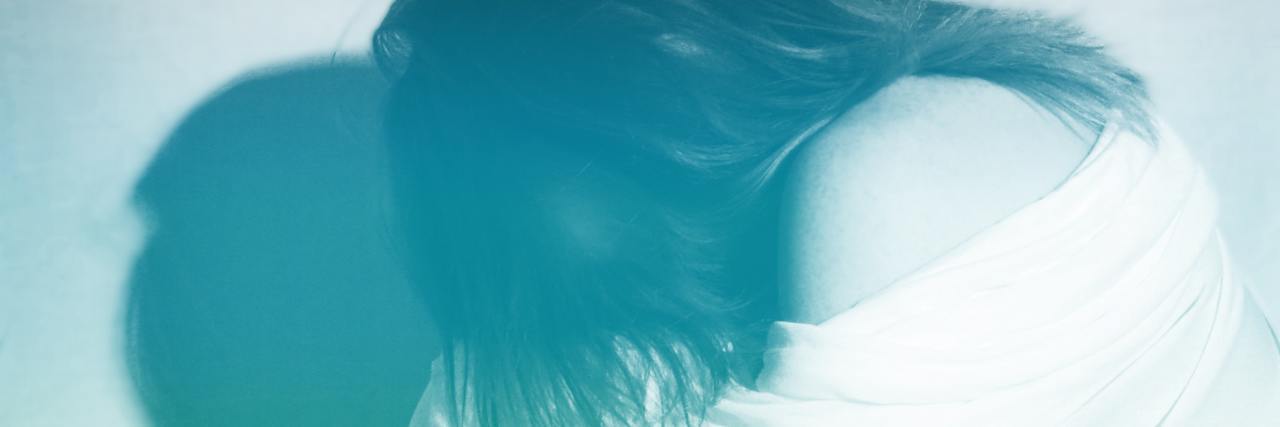 When Burying Depression and Anxiety Catches Up With You black and white colorised photo of woman wrapped in blanket