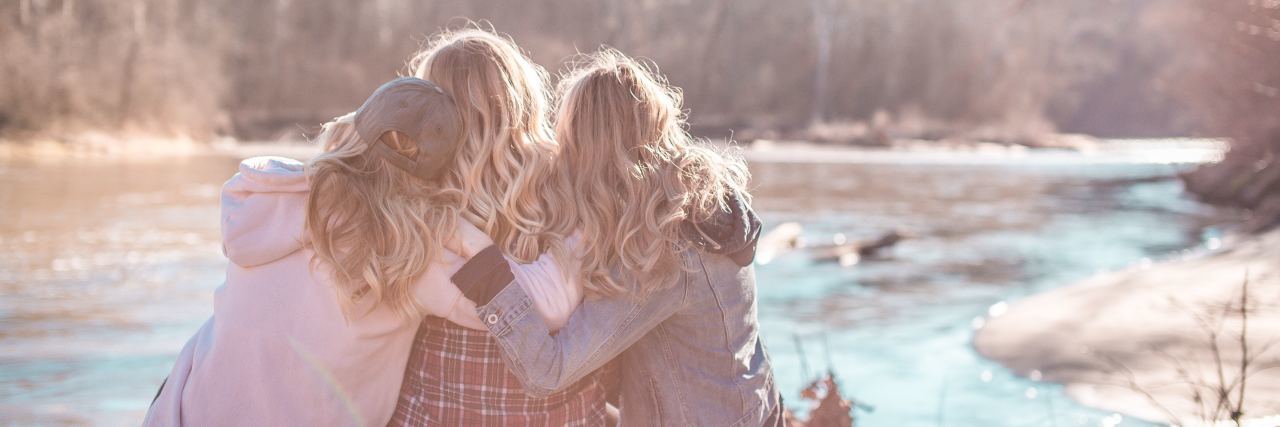 How to Use Your Mental Health Journey to Help Others group of women sitting close together embracing by river in state park