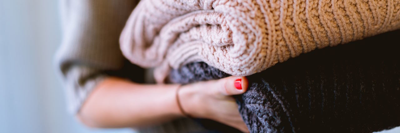 6 Everyday Tasks and Chores That Feel Hard With Depression A woman holding a pile of sweaters