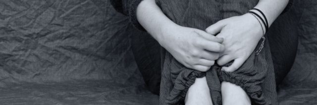black and white photo close up of woman hugging knees and bare feet