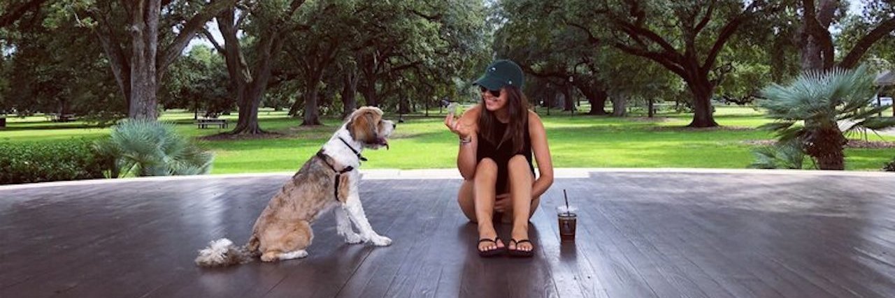 I Don't Label My Days as Good or Bad With Chronic Migraine a woman sitting with a dog