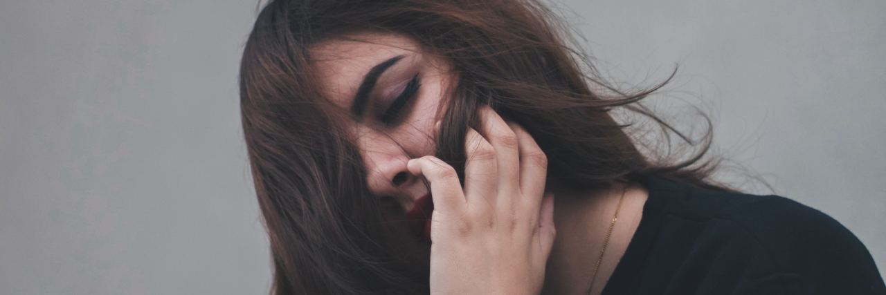 How to Tell the Truth Instead of Saying 'I'm Fine' woman leaning against wall with hair partially covering face