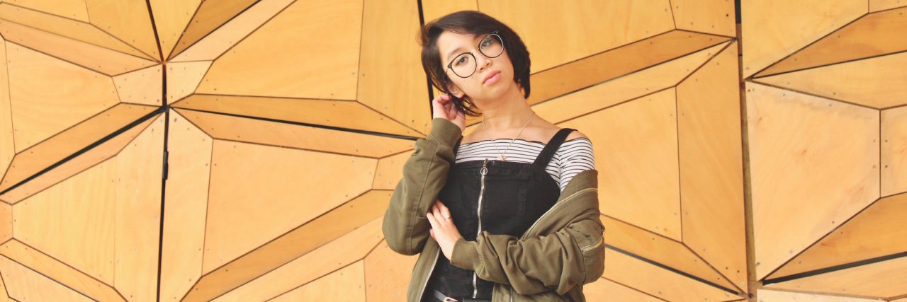 When Borderline Personality Disorder Makes You Feel 'Unlikable' woman standing in front of yellow geometric wall with sad expression