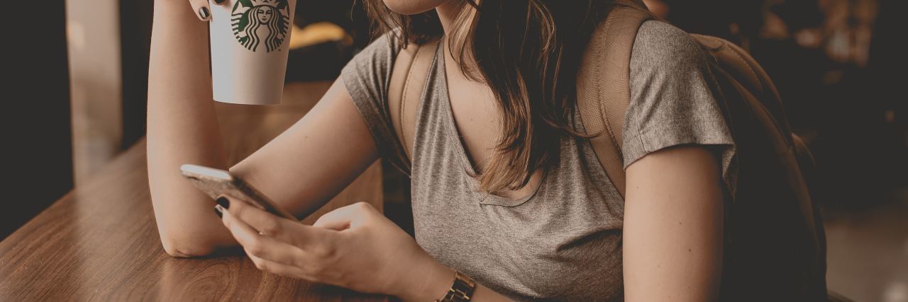 photo of young woman in coffee shop with smartphone