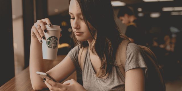 photo of young woman in coffee shop with smartphone