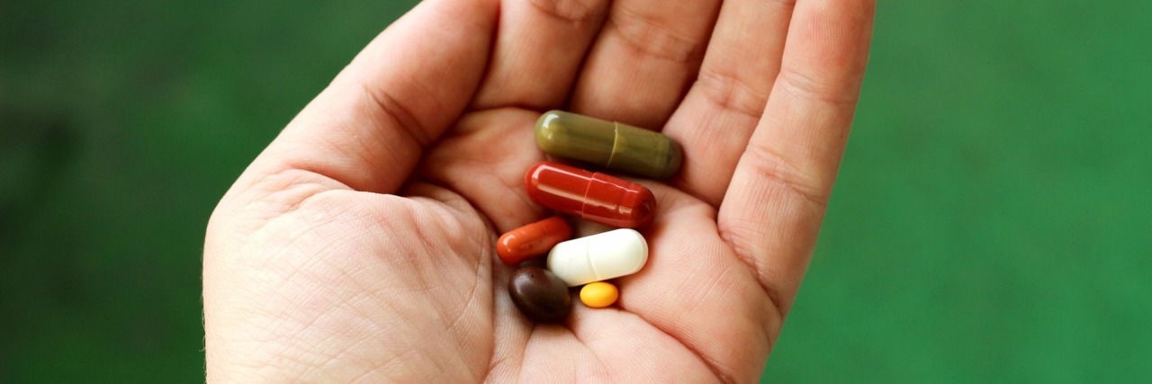 photo of hand holding pills with green background