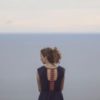 photo of woman standing at ocean alone looking out at horizon