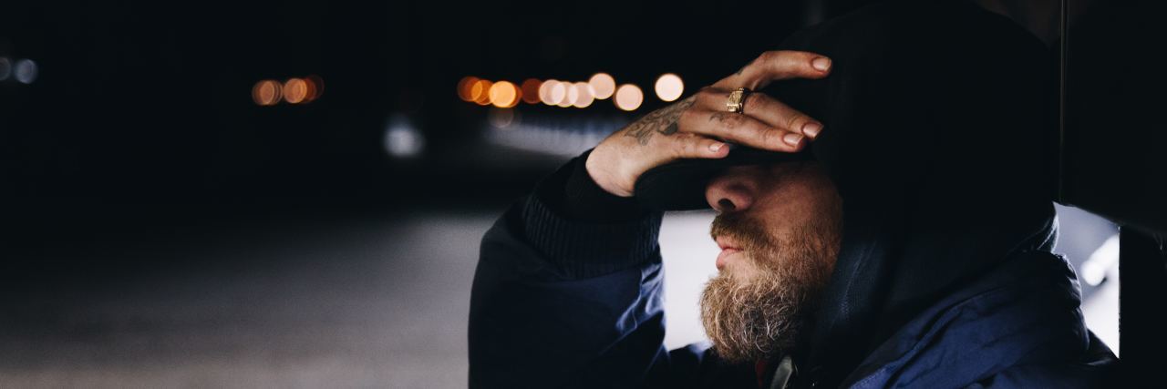 My Depression Returned After Years photo of bearded man sitting by side of road shielding eyes with hand