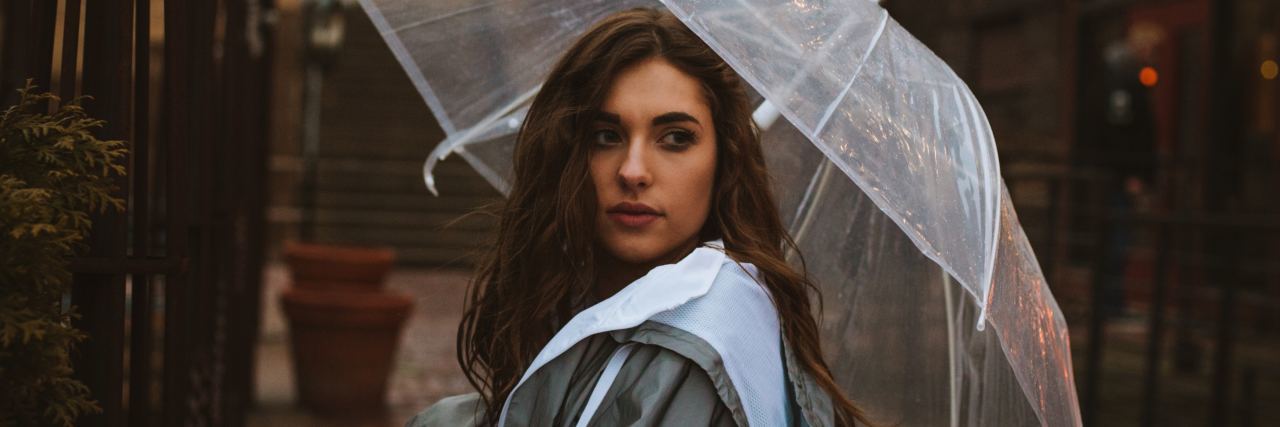 How to Stop Feeling Others' Emotions as a Highly Sensitive Person young woman standing in street with umbrella looking over her shoulder