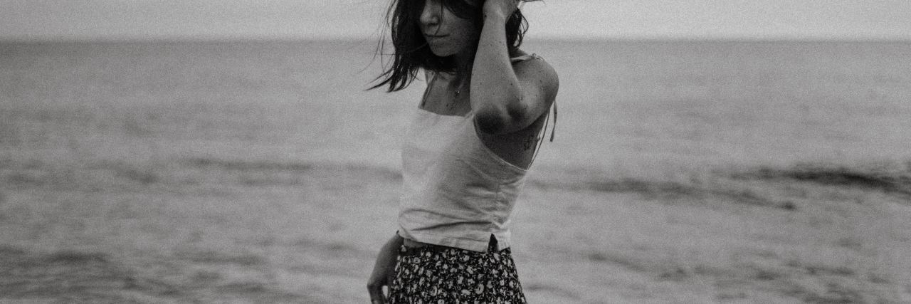 black and white photo of woman by sea with hand in hair
