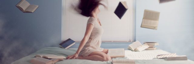 surreal photo of young woman sitting on bed while books fly into air around her