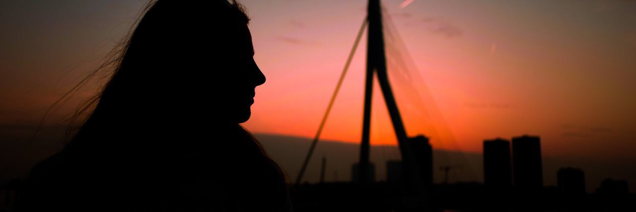 silhouette of a woman standing outside at sunrise