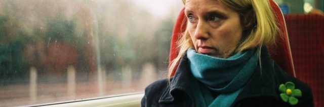 photo of woman looking serious looking out of window on train
