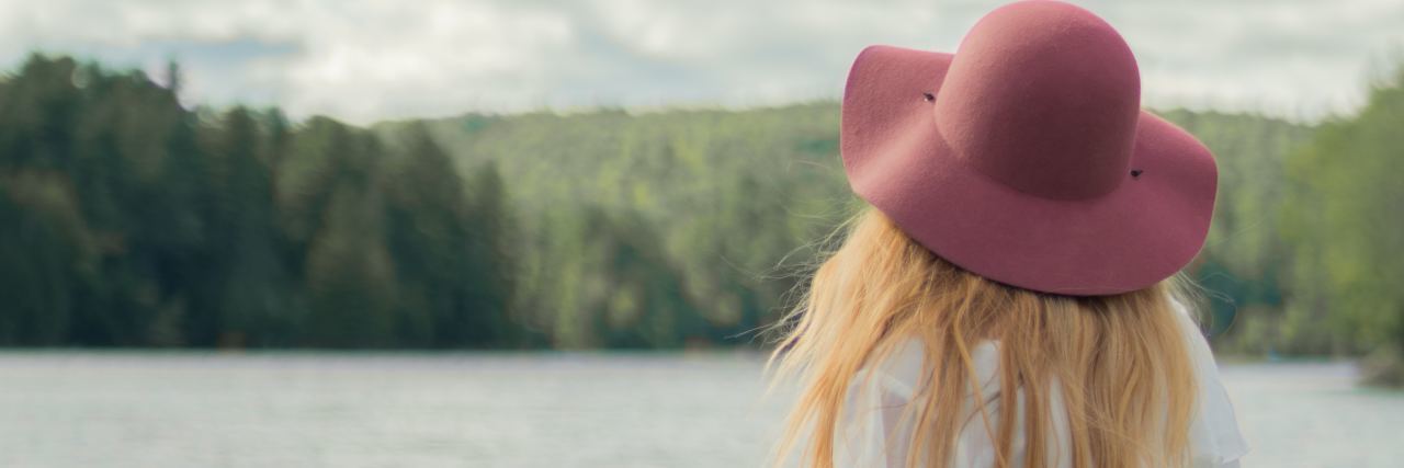 How to Deal With Perfectionism as a Highly Sensitive Person photo of blonde woman sitting on pier at lake looking at water and trees