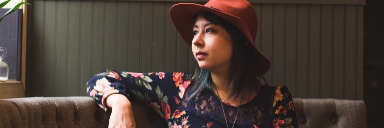 A Guide to Setting Resolutions With a Chronic Illness woman sitting at restaurant booth looking out window with cups on table