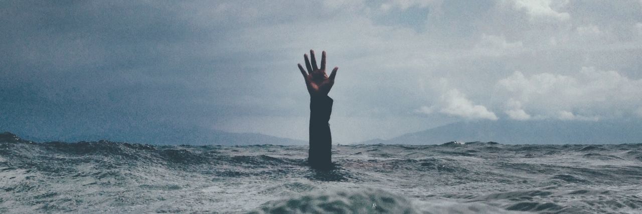 What the Diagnostic Criteria for BPD Really Means photo of hand reaching from ocean against backdrop of stormy skies