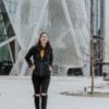photo of young woman with rucksack walking through college campus with large head sculpture behind her