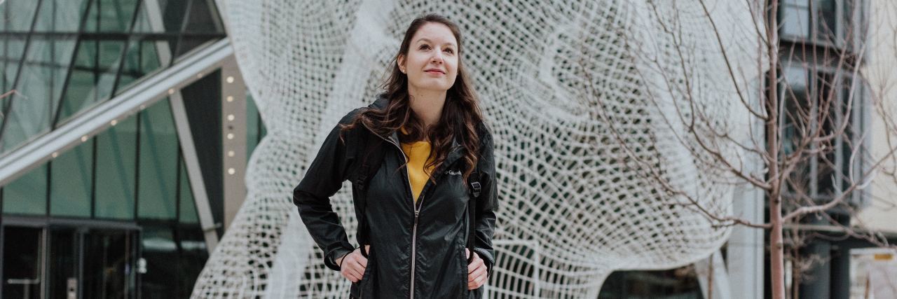 Tips for Chronic Migraine in College and University photo of young woman with rucksack walking through college campus with large head sculpture behind her