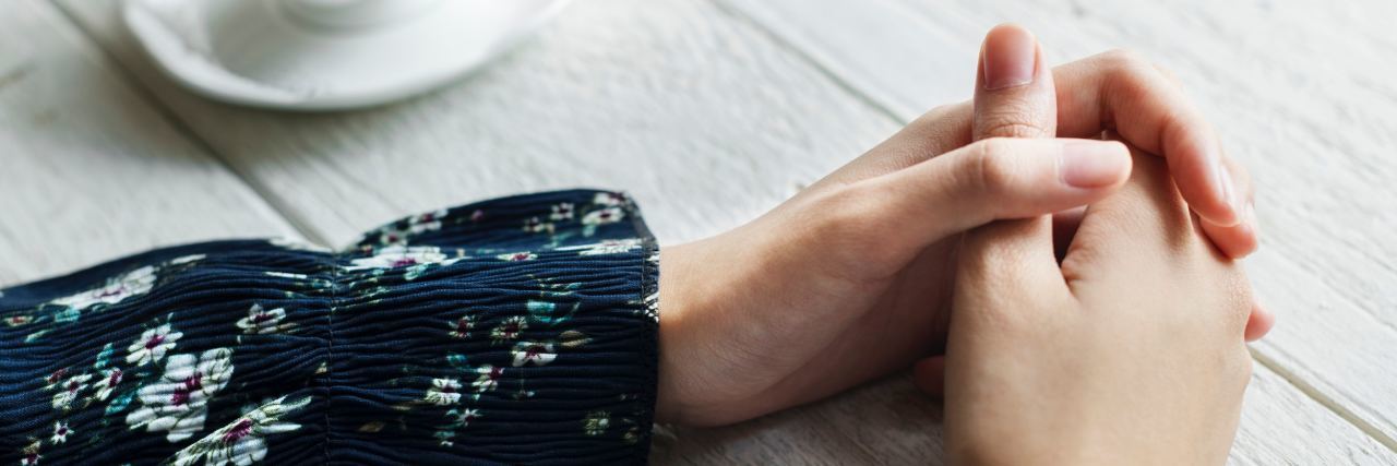 When You Put Off Getting Help for Anxiety close up photo of woman's hands on table clasped beside cup of tea