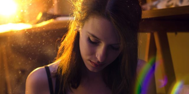 photo of young woman in golden sunlight with rainbow light flare