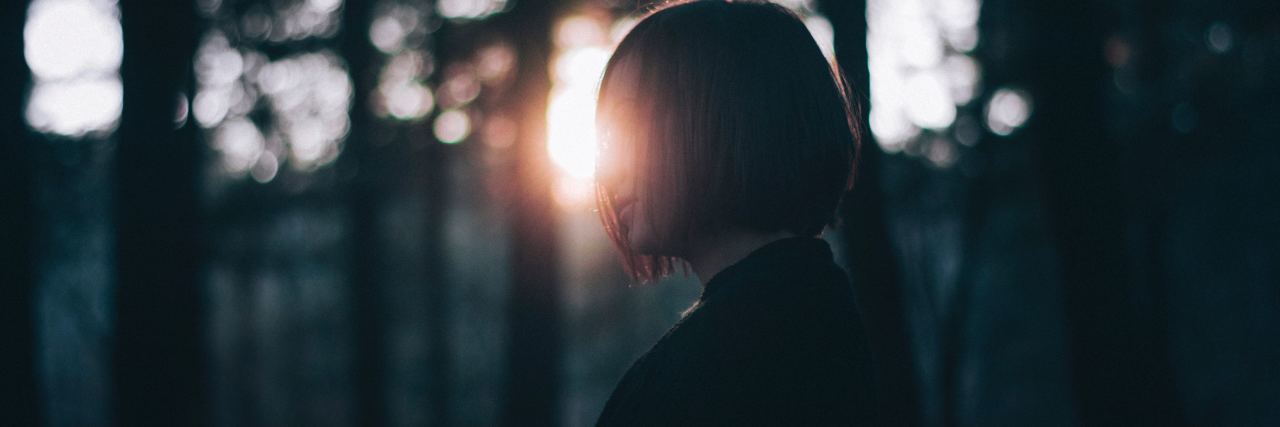 Why My Anxiety Makes Me Apologize All the Time photo of woman standing in forest framed by sunlight