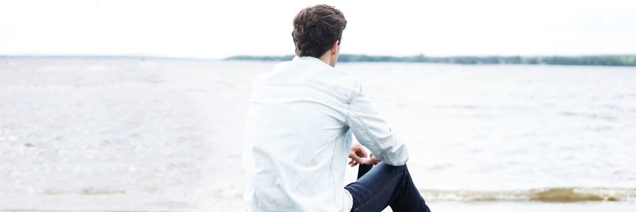 Having a Bad Day With Depression or Anxiety? Here's What to Know man sitting on beach looking out to sea with back to camera