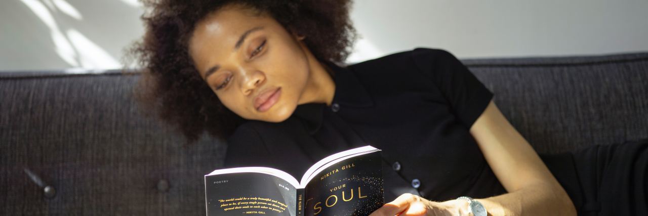 Tips for Getting Through Loneliness and Socializing woman lying on sofa reading book in sunlight