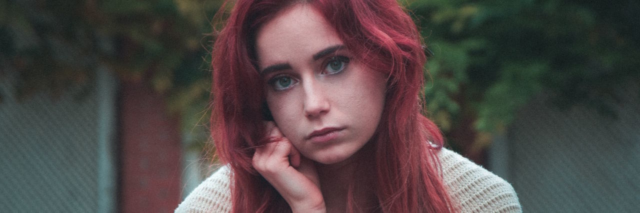 sad woman with red hair looking straight ahead