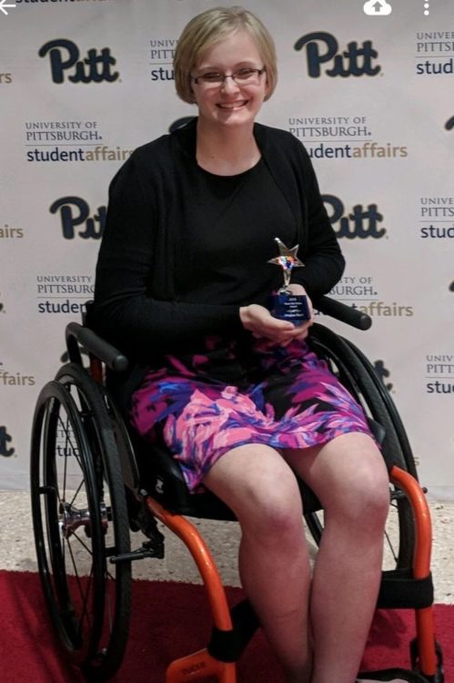 The author sitting in her wheelchair, smiling