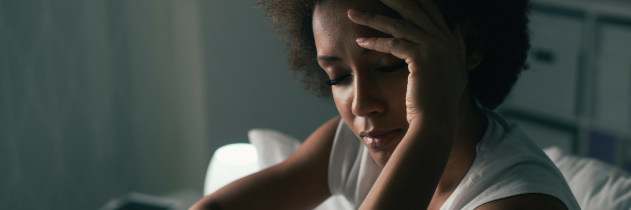 8 Ways to Cope If Sex Is Triggering Because of Past Trauma A photo of a woman sitting on a bed, looking down. The text on the photo reads: "8 Ways To Cope If Sex Is Triggering Because of Past Trauma"