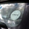 Rear window of a black Uber car with Uber sticker on the glass.
