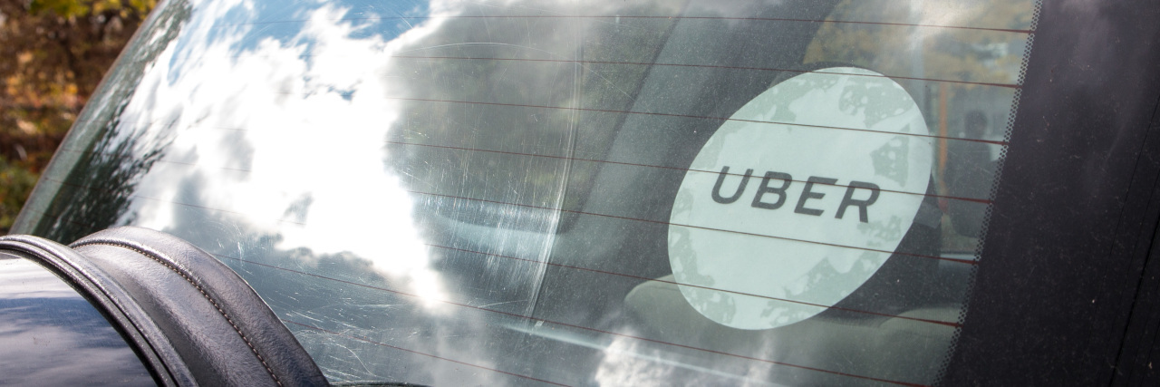 Using Uber as a Person With Autism Rear window of a black Uber car with Uber sticker on the glass.