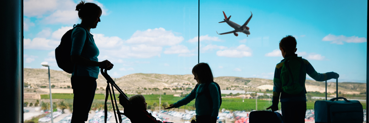 photo of mother and children silhouetted against airport sky