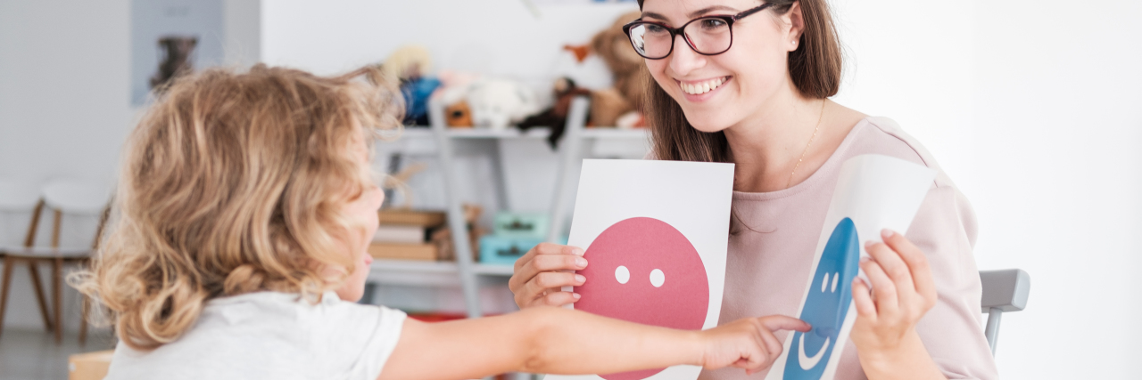 Pursuing a Late Autism Diagnosis Smiling counselor holding pictures during meeting with young student with autism.