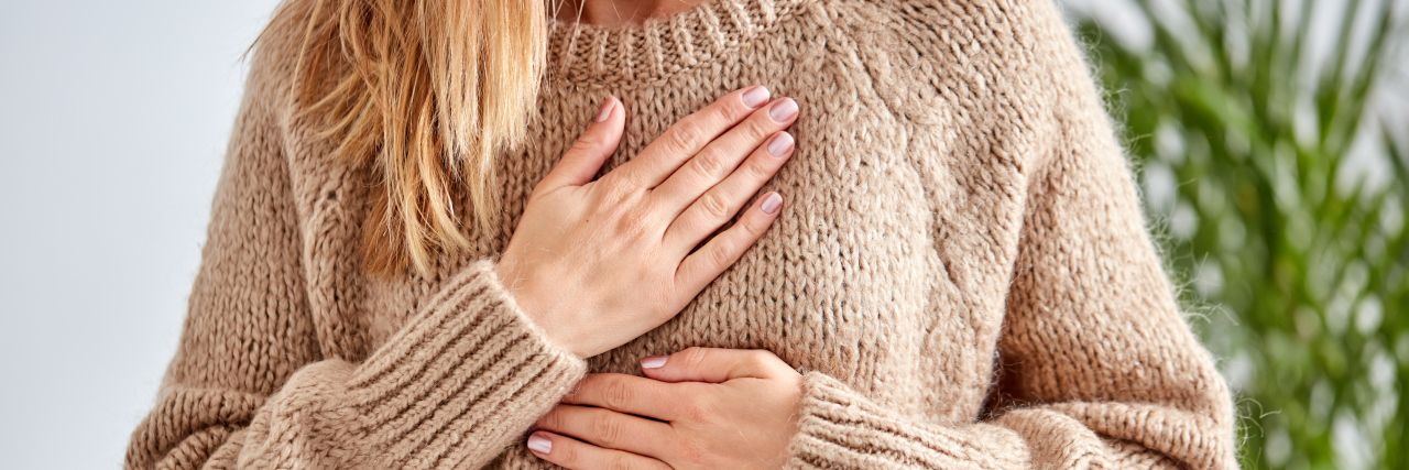 close up photo of woman with hands to chest