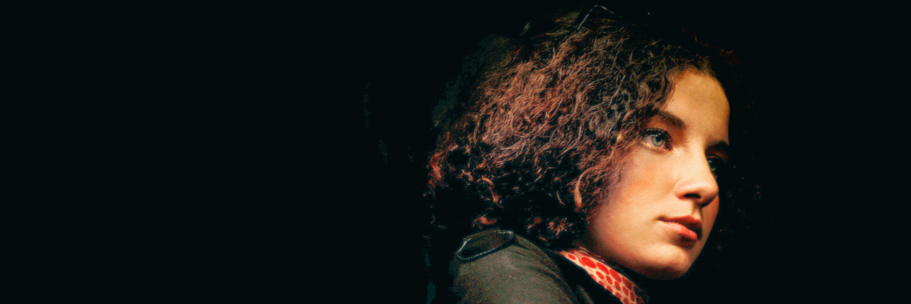 Struggling to Talk About Meniere's Disease With Friends and Family Woman with tan skin and curly hair looking thoughtfully into the distance.