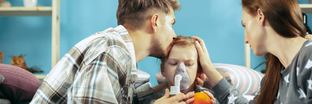 Mom and dad helping their child with a nebulizer treatment