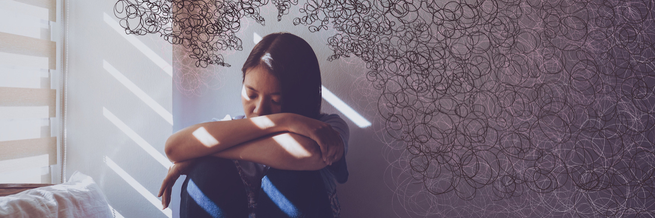 What to Remember During a Fibromyalgia Flare A woman sitting in bed hugging her knees.