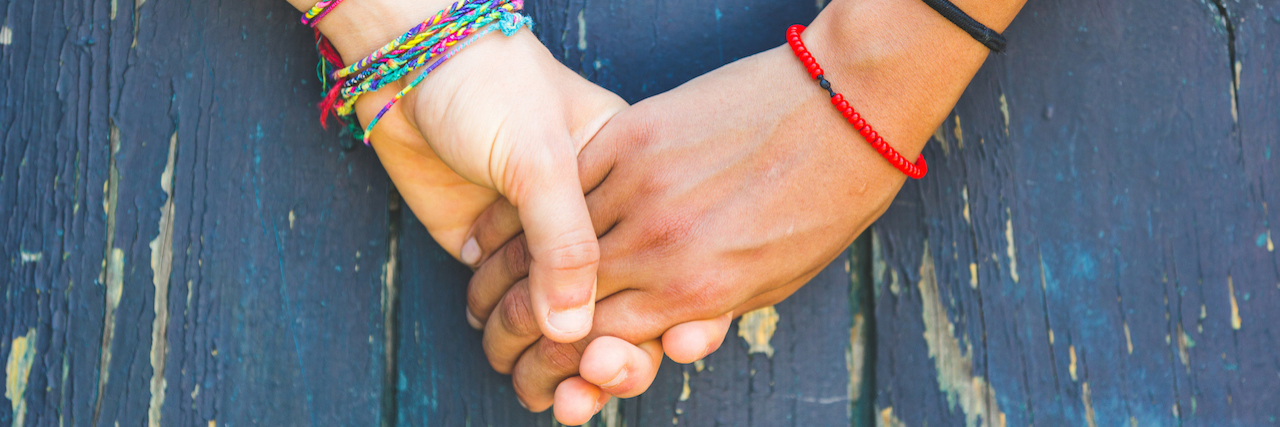 A Letter to Friends You've Lost Because of Your Illness Two women holding hands with a wooden background